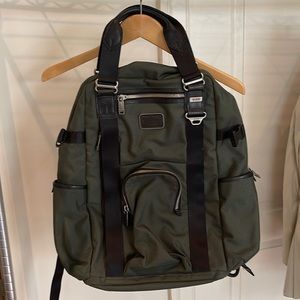 Tumi olive green nylon backpack with two handle grip on top.